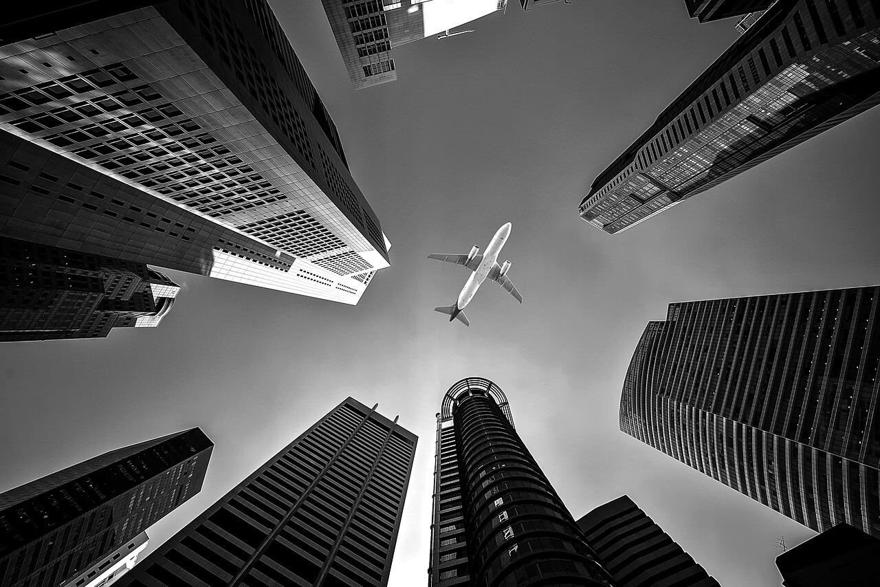 Tall city building with airplane flying over